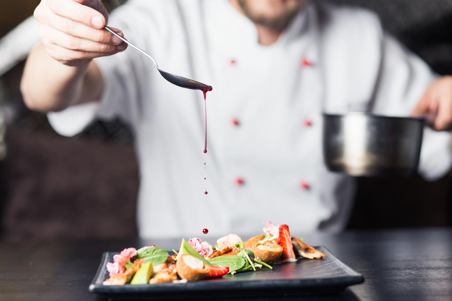 Chef-kok doet saus op het gerecht.
