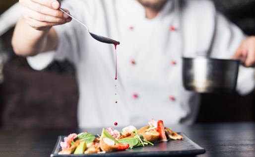 Chef-kok doet saus op het gerecht.